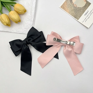 Elegant oversized satin bow hair clips in black and pink with long ribbons and metal clips