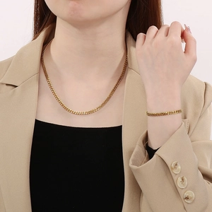 Ensemble élégant collier et bracelet en acier inoxydable doré porté par un mannequin