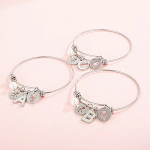 Detailed view of silver adjustable bangles with pearl and letter charms A, B, and C