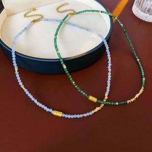 Détail de colliers en perles de pierres bleues et vertes avec perles dorées sur écrin