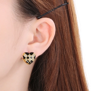 Close-up of heart earrings with black enamel checkerboard pattern and zircon inlay