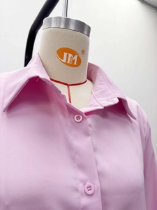 Detailed shot of pink lapel shirt featuring matching buttons and woven fabric texture