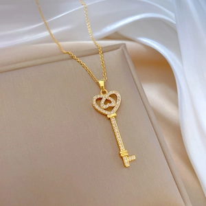 Close-up of gold heart key pendant with crystals on a soft beige cushion