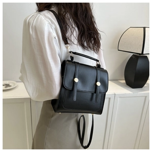 Vue arrière d'un sac à dos noir en cuir avec boucles dorées porté par un mannequin