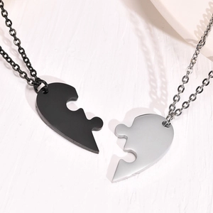 Close-up of interlocking puzzle piece heart pendants in black and silver steel