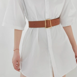 Detail of a brown wide waist belt with a golden square metal buckle on white dress