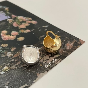 Polished silver and gold dome earrings showcased on a vintage floral magazine background