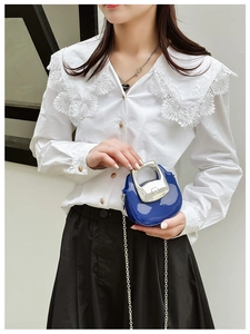 Detail of blue glossy mini bag with silver chain strap and metal handle on a model