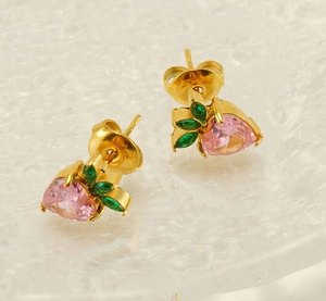 Detailed macro of gold strawberry stud earring with pink zircon and green leaf gems