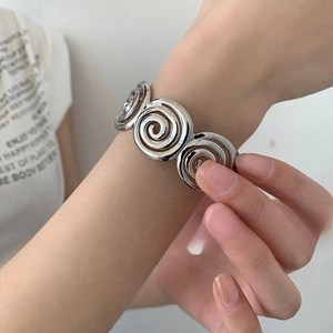 Polished silver geometric spiral bracelet featuring a modern multi-layered swirl design