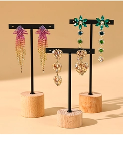 Three pairs of elegant tassel and floral earrings on a black metal and wood jewelry stand