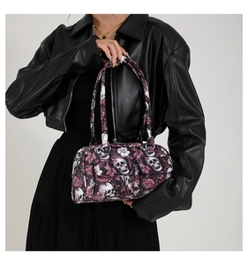 Close-up of gothic floral skull print on a black shoulder bag with metal zipper