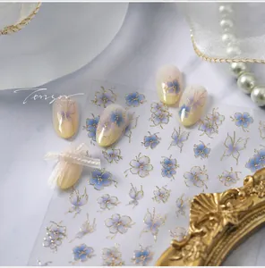 Close-up of blue floral and butterfly nail stickers with gold embossed details