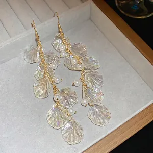 Elegant gold earrings with shimmering shell petals and delicate pearls in jewelry box