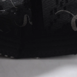 Detail of black mesh fabric with curved pattern texture and woven strap edge on cap