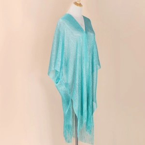 Detailed macro view of light blue shimmering knit fabric and long tassel fringes on the shawl