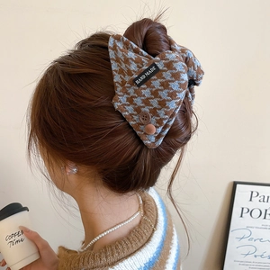 Detail of checkered fabric hair claw clip with hand made label on a model's hair