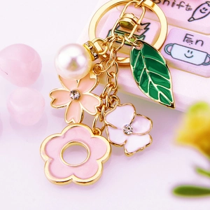 Detail of cherry blossom metal keychain with white pearl, pink enamel flowers and rhinestones