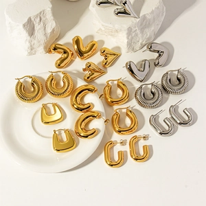 Minimalist chunky geometric hoop earrings in gold and silver finish on white stone decor