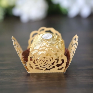 Close-up of golden laser-cut hollow rose lace paper box holding a chocolate candy