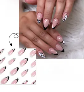 Detail of almond-shaped almond French press-on nails with black tips and white hearts