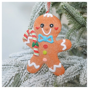 Sparkly gingerbread man ornament with candy cane hanging on a snowy Christmas tree