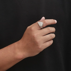 Detailed close-up of a triangular silver stainless steel ring worn on a finger