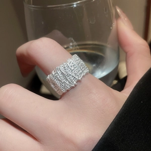 Close-up of a wide silver ring with complex woven lava texture on model's hand