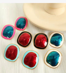 Detailed macro view of irregular geometric earrings with contrasting colorful resin and gold rims