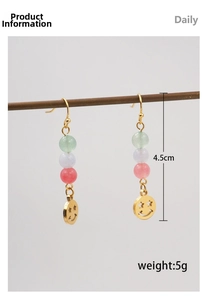 Detail view of ethnic long drop earrings with colorful beads and gold smiley charm