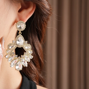 Vue détaillée de boucles d'oreilles géométriques dorées avec cristaux sur le mannequin