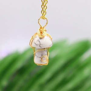 Macro shot of gold wire-wrapped howlite mushroom pendant necklace with natural stone texture