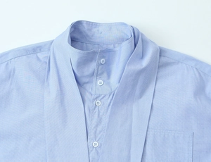 Close-up of light blue long-sleeve shirt collar and chest pocket with button detail