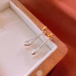 Minimalist gold and silver teardrop earrings with irregular texture in a wooden gift box
