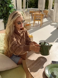Chic brown turtleneck cable knit sweater for women in a warm autumnal outdoor setting