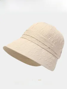 Detail of beige bucket hat showing textured crepe fabric and available color swatches