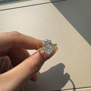 Close-up of luxury gold ring with oval-cut clear gemstone and pavé-set zircons on hand