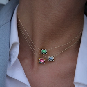 Three-layer gold necklace with checkered enamel gemstone pendants on a model wearing a suit