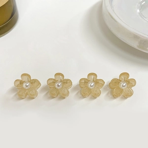 Detailed close-up of small amber flower hair claws with embedded white pearls set of 4