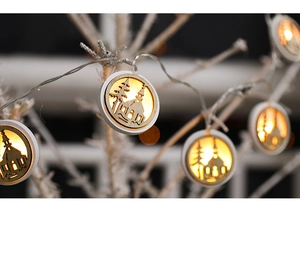 Detail of wooden LED star ornaments with cutout house patterns on snowy branches