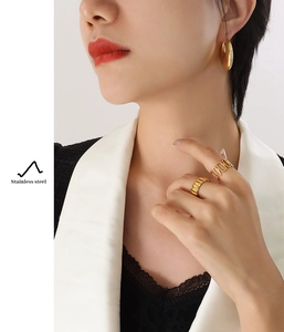 Detail of gold-plated stainless steel U-shaped earrings and rings on model