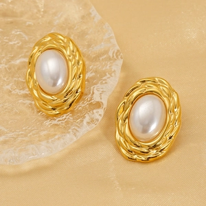 Vintage oval gold braided earrings with creamy pearl center on elegant silk background