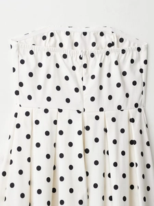 Détail de robe blanche à pois avec fermeture éclair au dos et texture de tissu plissé