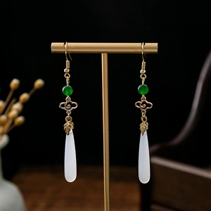Macro shot of long beaded tassel earrings with green beads and white teardrop pendants