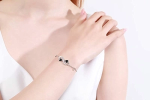 Detail of 925 silver infinity bracelet with black hearts and diamonds on a wrist