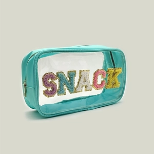 Détail d'une trousse en PVC menthe avec lettres SNACK brodées et bordure pailletée