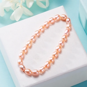 Pink freshwater pearl elastic bracelet displayed on a white textured jewelry gift box