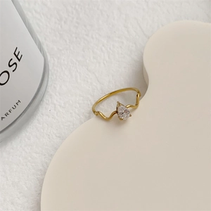 Close-up detail of a delicate wave-shaped 18K gold ring with a pear-cut teardrop diamond.