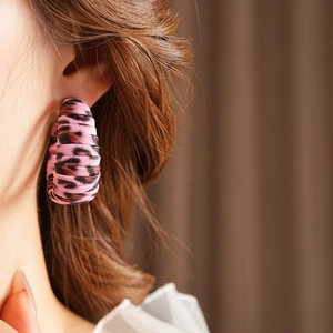 Close-up of pink leopard print C-shape leather earrings on model in vintage style