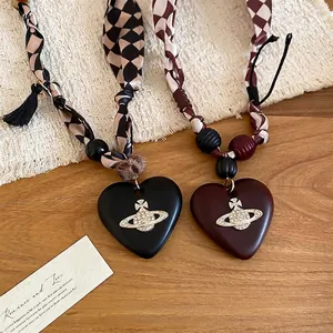 Vintage heart necklaces with Orb charms and patterned ribbon cords on wooden surface